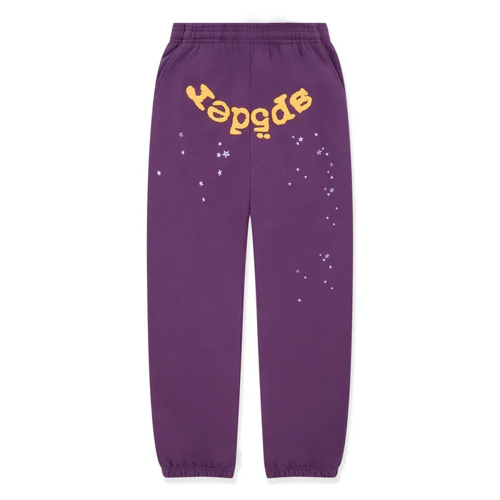 The 100% Cotton Sp5der Sweatpants are unisex purple jogger pants with elastic cuffs and waistband, featuring a yellow upside-down "sp5der" logo near the top and small white star graphics on one leg for relaxed streetwear style.