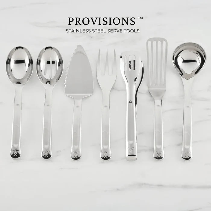 Seven Hestan Provisions® Serving Tools—including a serving spoon, slotted spoon, 10.5-inch Stainless Steel Pie & Cake Server, meat fork, salad tongs, slotted turner, and ladle—are arranged side by side on a white marble surface.