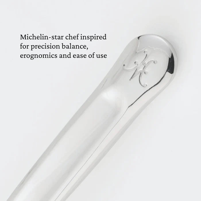 A close-up of the polished handle of the Hestan Provisions® 10.5-inch Stainless Steel Serving Fork, featuring an engraved logo. Text on the left reads: Michelin-star chef inspired for precision balance, ergonomics and ease of use—hallmarks of exceptional chef’s tools like this stainless steel serving fork from Hestan Provisions®.
