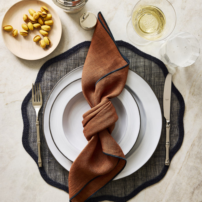 Bali 18/10 stainless steel flatware set with bamboo-inspired handles on a table setting with a white plate and brown napkin.
