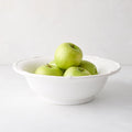 White ceramic serve bowl with molded bamboo detailing, filled with green apples.