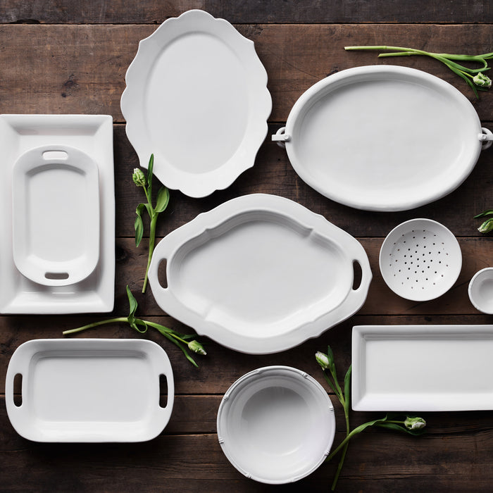 White ceramic serveware collection with bamboo detailing on a wooden surface.