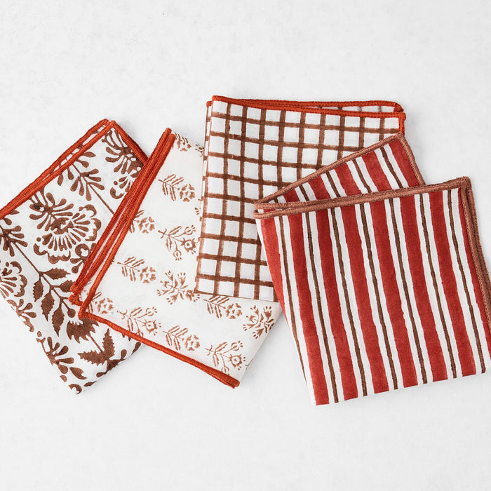 Set of four 10-inch cotton appetizer napkins with brick red and camel brown block prints and embroidered edges.
