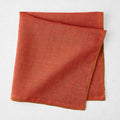 22-inch square brick red linen napkin with contrasting camel brown embroidered tipped stitch edging.