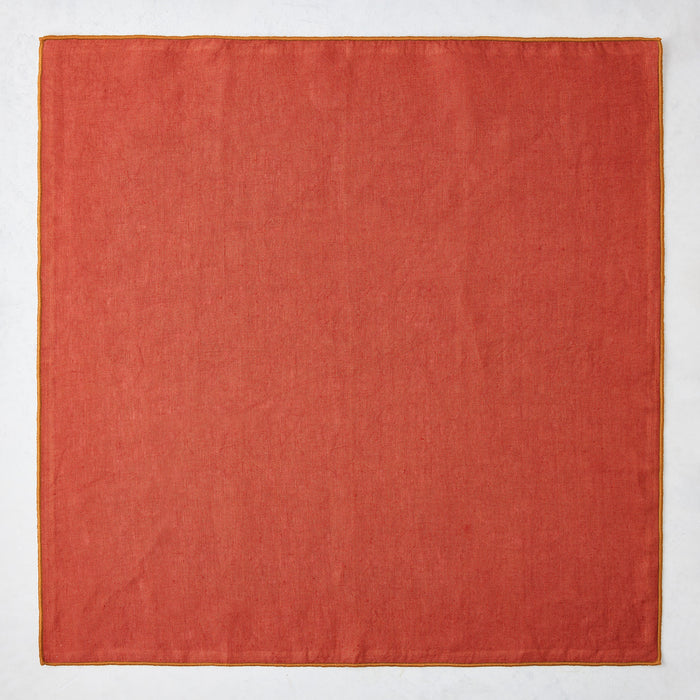 22-inch square brick red linen napkin with a contrasting camel brown embroidered tipped stitch edge.