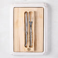 Jean Dubost stainless steel carving knife and fork set on a removable oak wood insert inside a white ceramic cutting board.