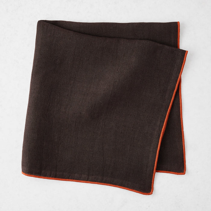 22-inch square chocolate brown linen napkin with a contrasting brick red embroidered tipped stitch edge.