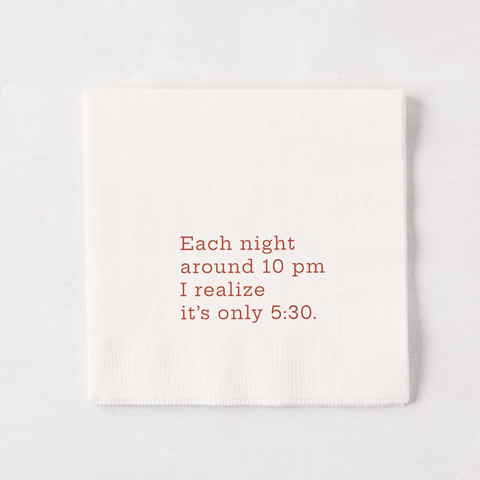 White 5.5-inch square 3-ply paper cocktail napkin with brown text reading Each night around 10 pm I realize it’s only 5:30.
