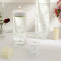 Decorative candles and water vases with floating beads on a table.
