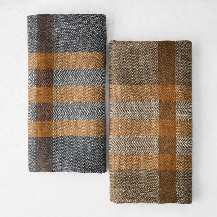 Two 21-inch square linen napkins featuring a graphite and brown herringbone plaid pattern on a white background.
