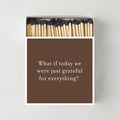 Oversized matchbox in brown with white text reading Grateful for Everything, containing 4-inch matches with black tips.