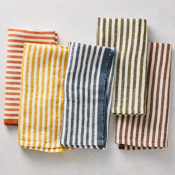 Set of five 21-inch square linen napkins featuring multicolored ticking stripes on a white base.