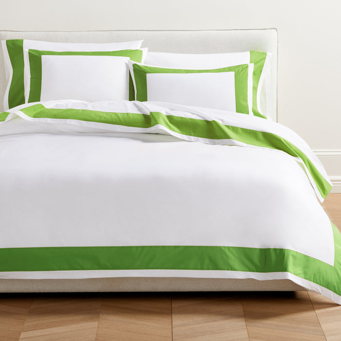 Set of 2 Green Wide-Band Percale Pillow Shams and matching duvet cover on a bed.