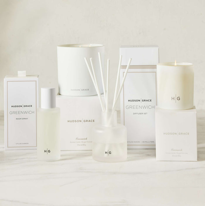 Hudson Grace Greenwich white room spray, diffuser, and candles in various sizes on a white surface.