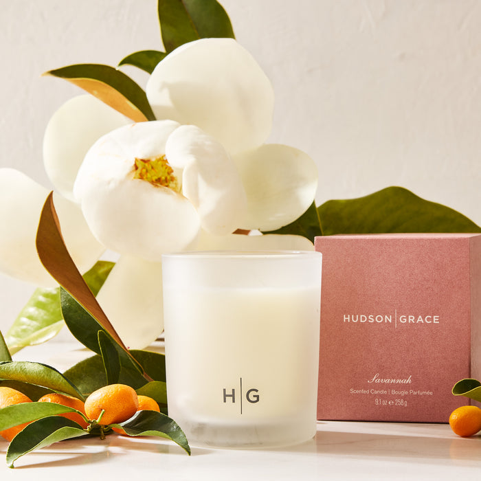 Hudson Grace Savannah Scented Candle in a frosted glass jar with a pink box, magnolia, and kumquats.