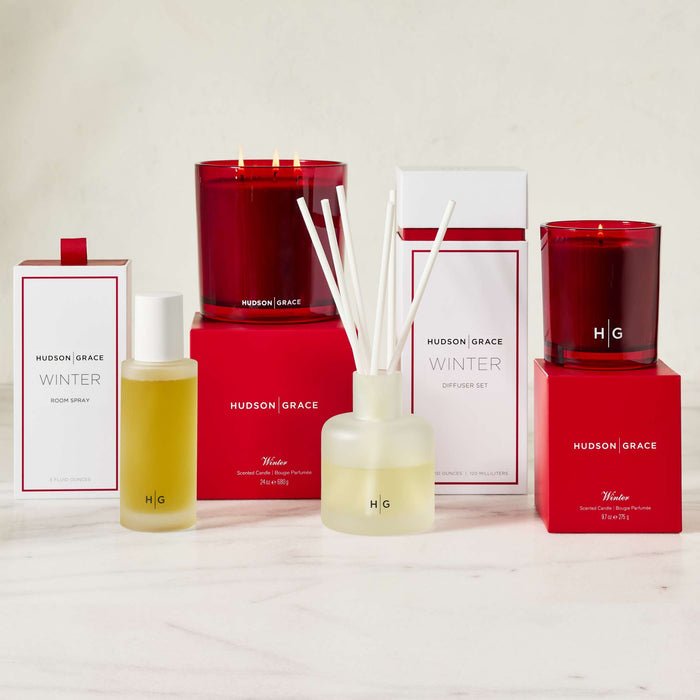 Hudson Grace Winter collection: red candles, room spray, and reed diffuser with white reeds.