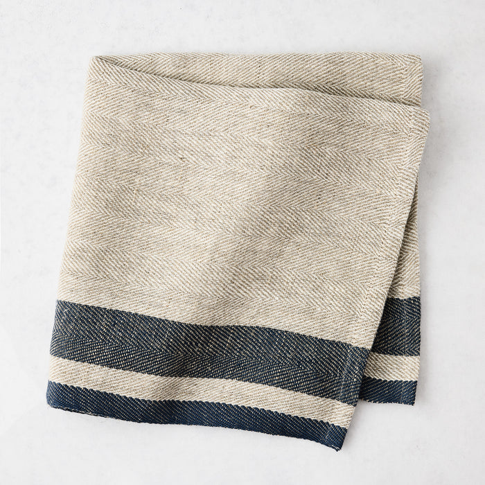 Lexington Blue Stripe Border Napkin, natural linen-cotton blend with navy blue stripes, folded.