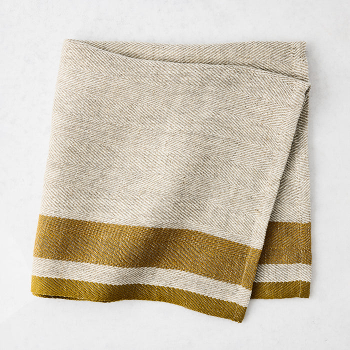 Lexington Gold Stripe Border Napkin, natural linen-cotton blend with gold striped edges, folded.