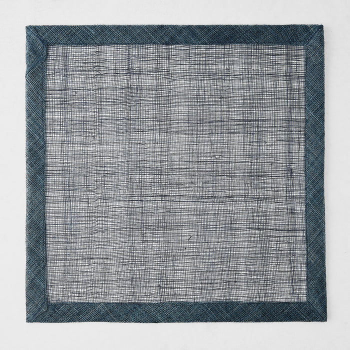 Navy blue square placemat made of woven abaca fibers with a semi-transparent center and solid border.