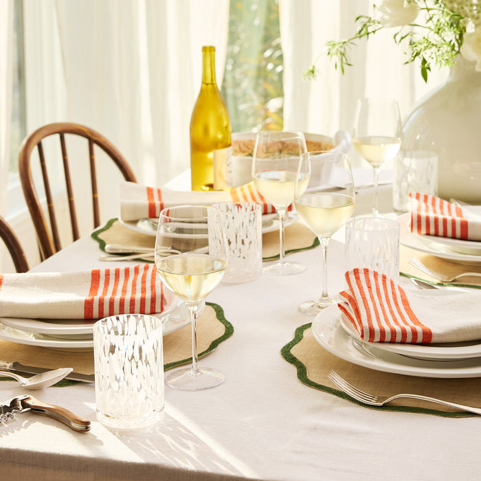 Newport Green Border Scallop Placemat, natural abaca with green edge, set on a dining table.