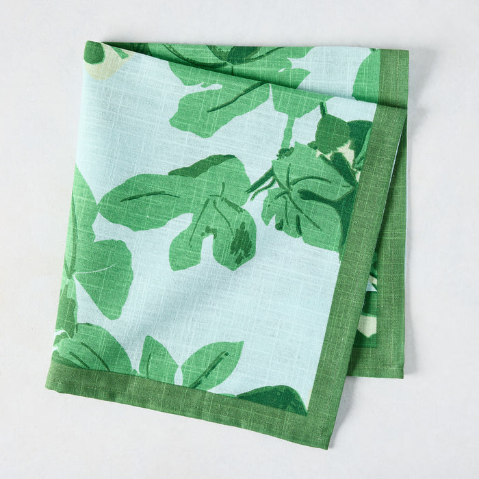 Pale blue cotton slub napkin with bold green fig leaf print and a solid green border.