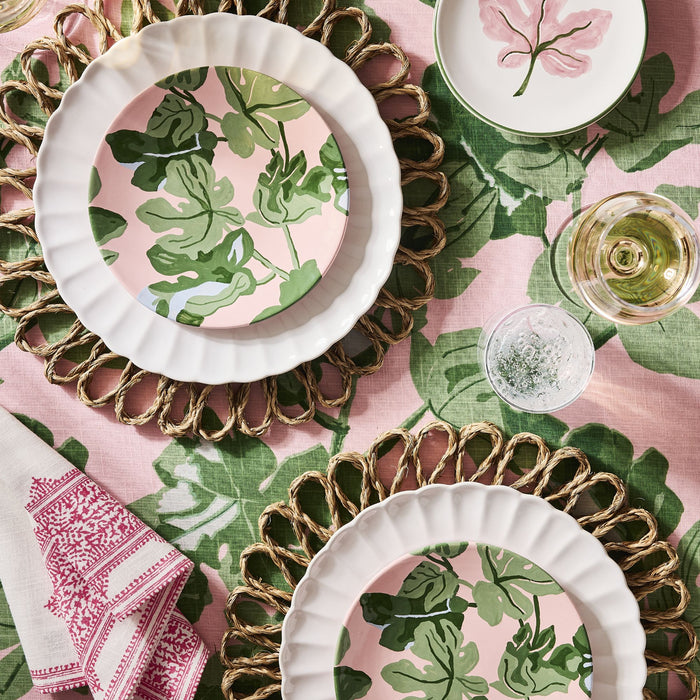 Peter Dunham + Hudson Grace hand-painted pink ceramic salad plate with green fig leaf pattern on a woven placemat.