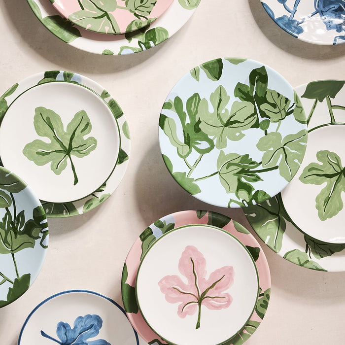 Hand-painted ceramic salad plates featuring green fig leaf patterns on pink, white, and light blue backgrounds.
