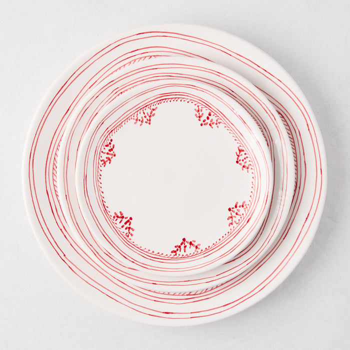 White ceramic appetizer plates with hand-painted red striped and dotted borders, stacked.
