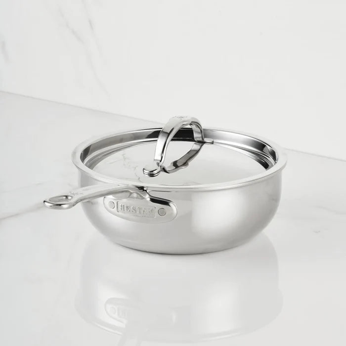 A ProBond Luxe® Polished Clad Stainless Steel Saucier Pan, 2-Quart, with a lid rests on a reflective white surface. This pan, part of ProBond Luxe®’s professional clad stainless steel cookware collection, features a long handle and a rounded body, with the brand name ProBond Luxe® engraved on the handle base.