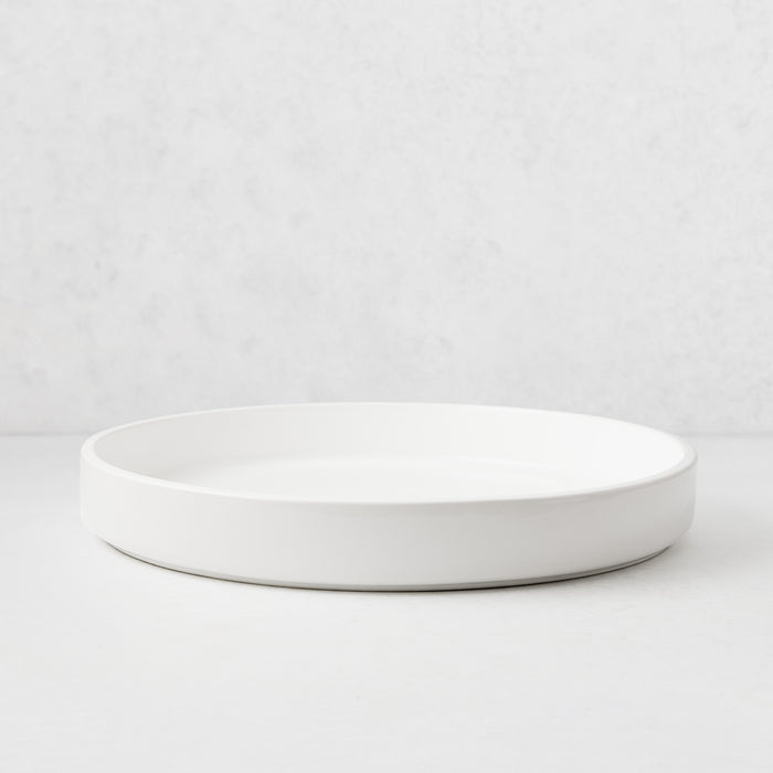 Round white ceramic bar tray with a wide base and low edges, made in Italy.
