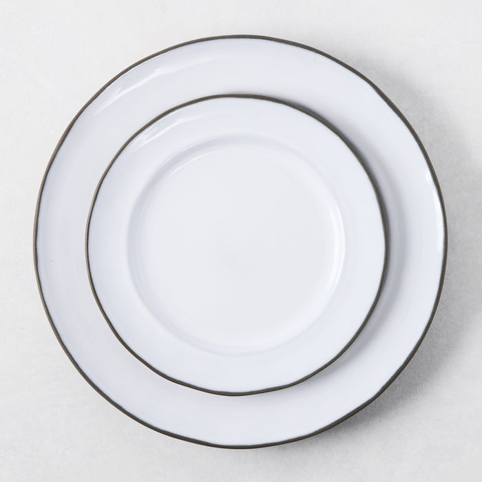 Two white enamelware plates with dark rims, stacked.