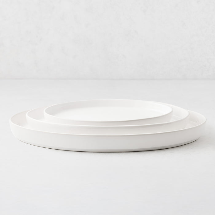 Set of three white stoneware oval nesting platters with a minimalist design on a white surface.