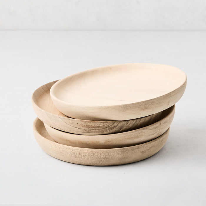 Stack of four 6-inch round appetizer plates hand-carved from light-toned walnut wood with a smooth, low-lip profile.