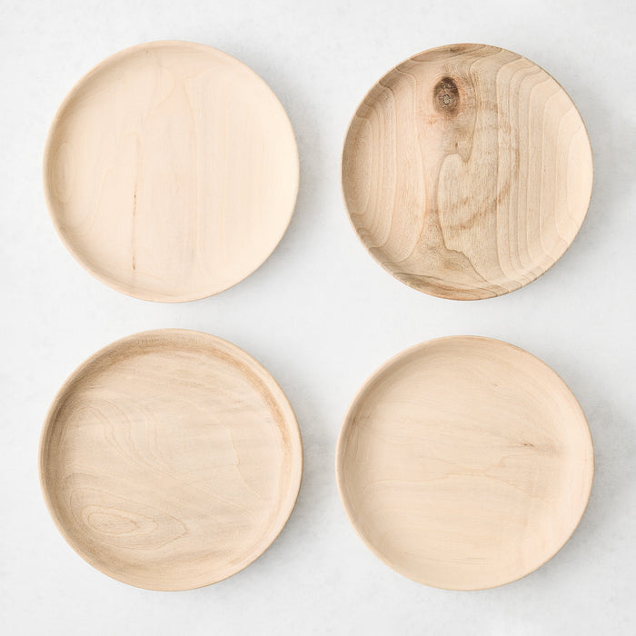 Set of four 6-inch round appetizer plates handcrafted from natural walnut wood with visible grain patterns.