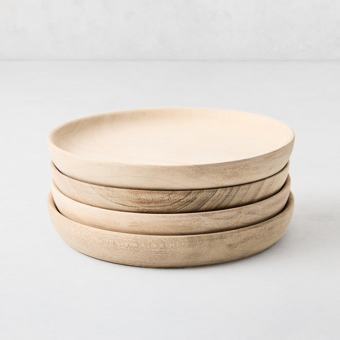 Stack of four 6-inch handcrafted walnut wood appetizer plates with natural grain and low-profile rims.